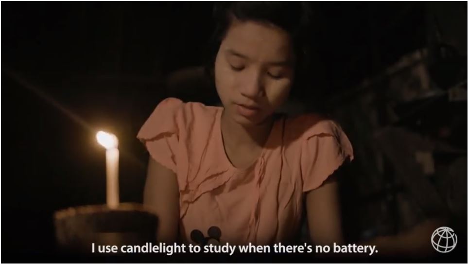 A young girl reads by candlelight in Myanmar