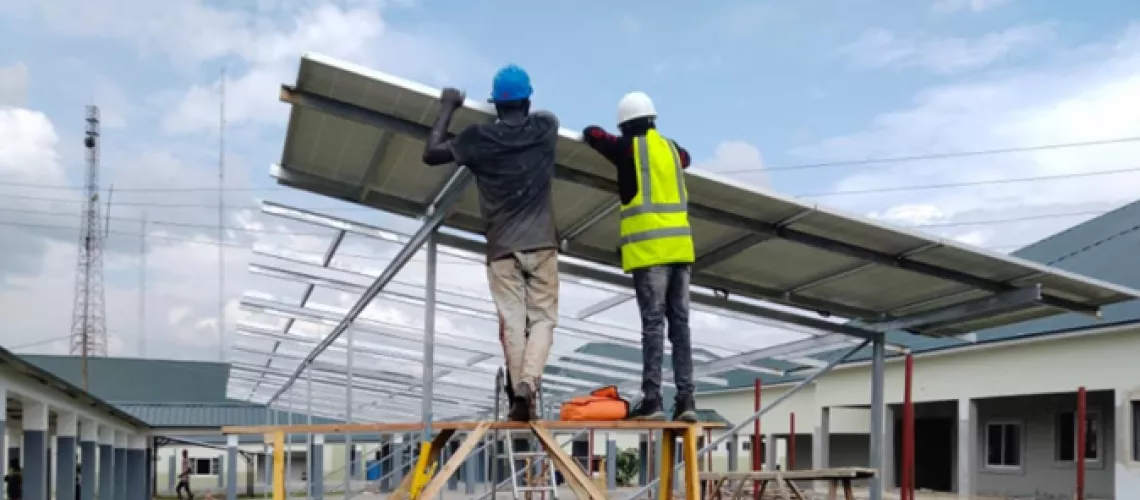 workers install a solar array at a large hospital in Nigeria.