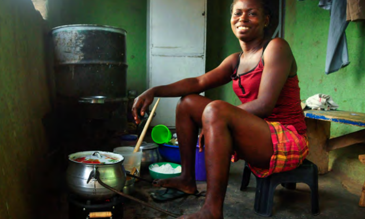 Image Source: ©Envirofit Person sitting on a small stool while preparing a meal