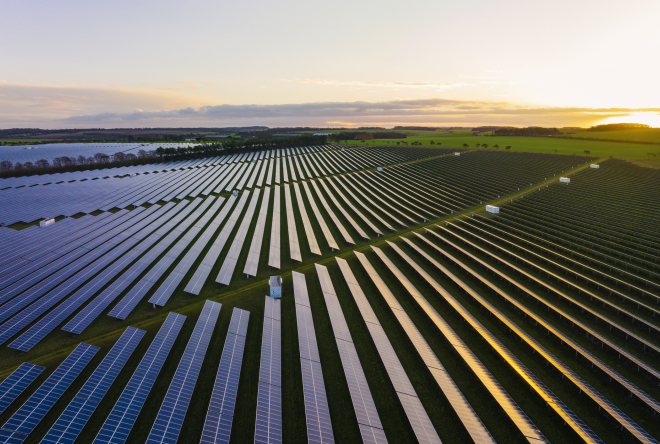 Aerial view of a large solar power installation covering a plain green land.