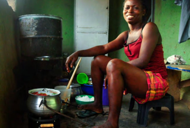 Image Source: ©Envirofit Person sitting on a small stool while preparing a meal