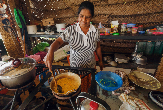 Person stirring food in a pot on a stove in a kitchen