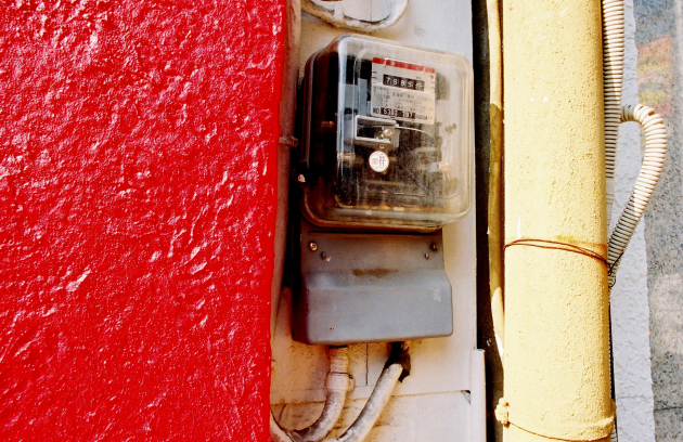 Electricity meter mounted on an exterior wall with connected wiring.