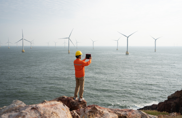 Technician observing offshore wind turbines over the see