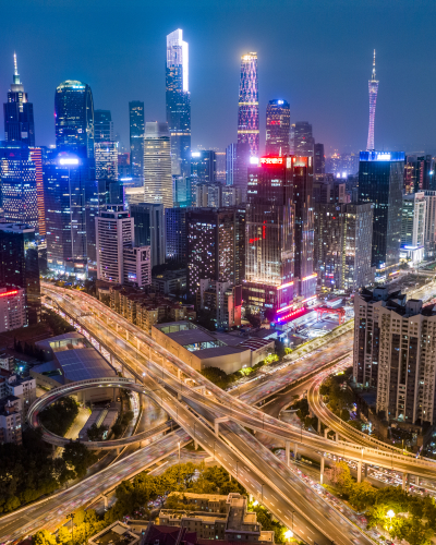 Nighttime city skyline with illuminated skyscrapers and elevated highways weaving through downtown.