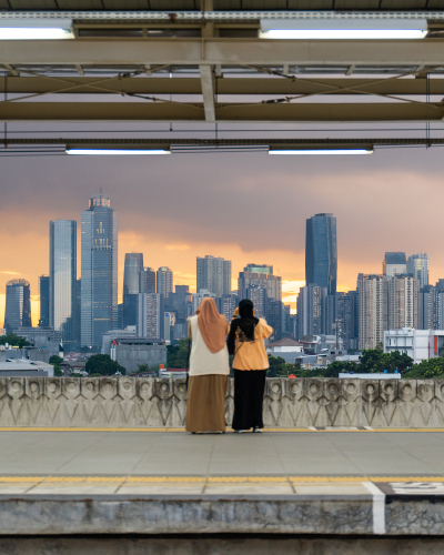 Two people taking picture of cityscape from a railway station