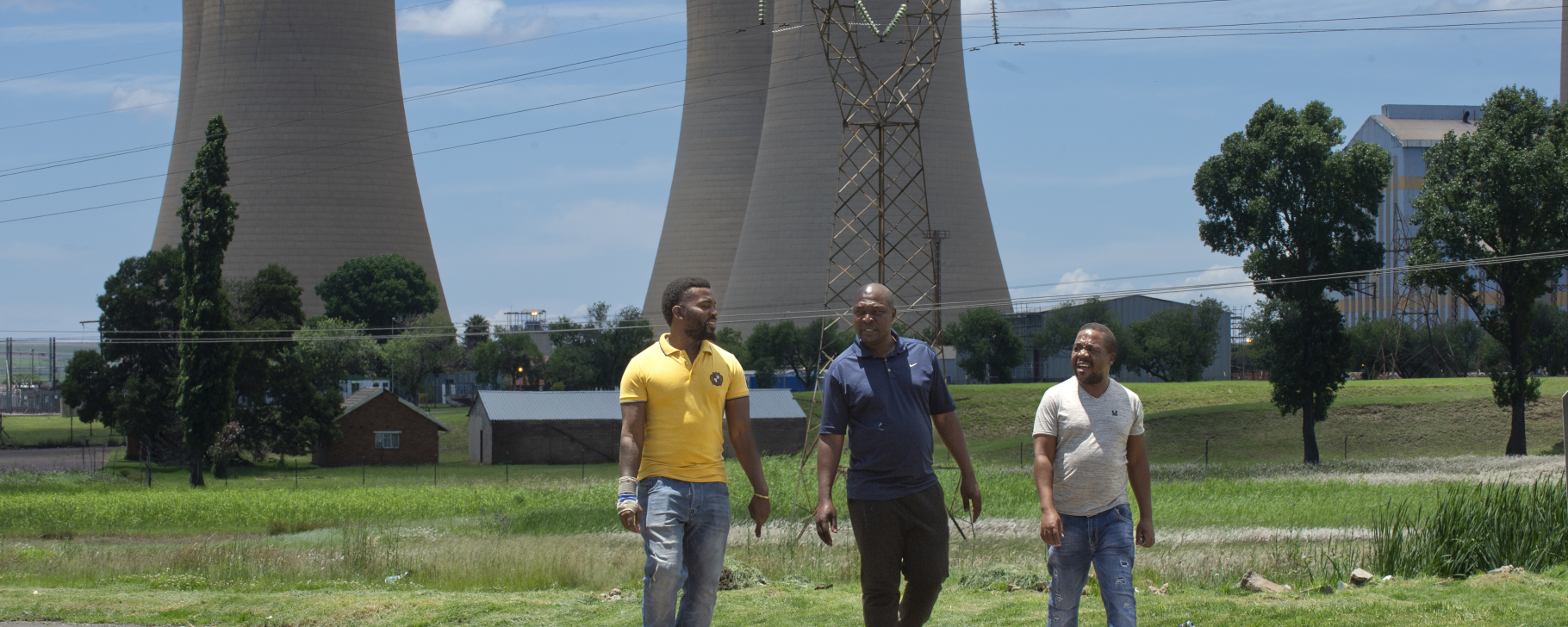 Three people walking away from a coal plant