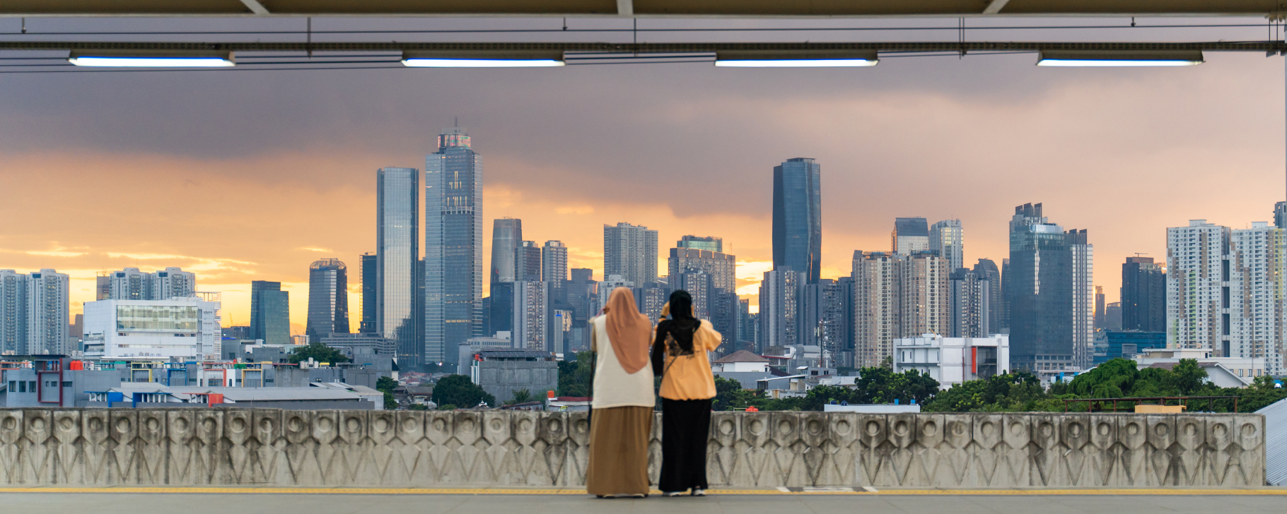 Two people taking picture of cityscape from a railway station