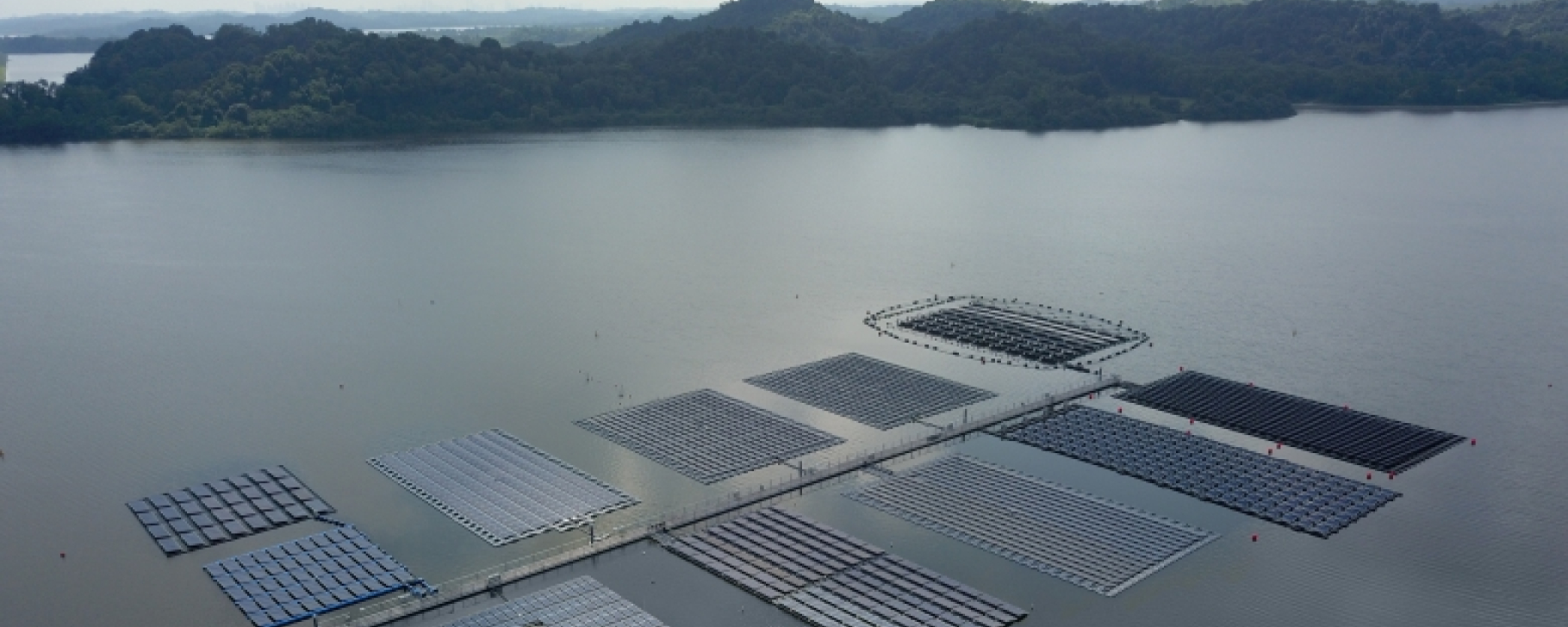 Aerial view of a large utility-scale floating solar photovoltaic (PV) system installed on a calm body of water