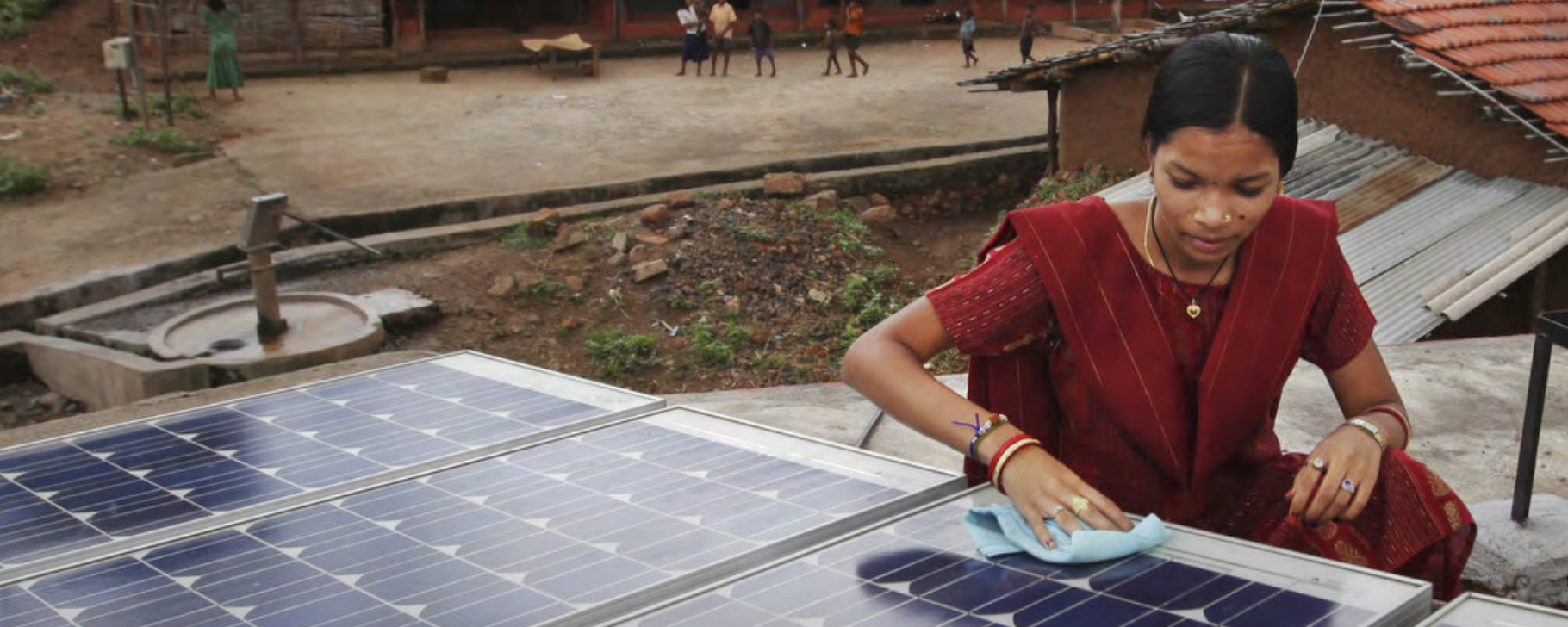 Jobs in Energy Person cleaning a solar panel installation on a rooftop in a rural community