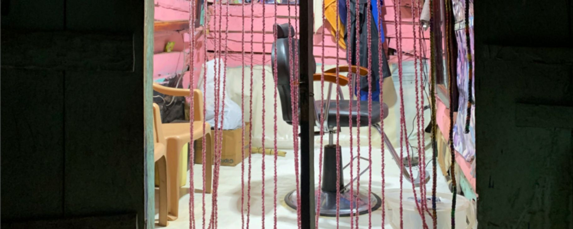 Beyond Connections: Informing the Next Decade of Energy Access Policy and Investment A barber shop with pink beaded curtains, a barber chair, and walls decorated with pictures.
