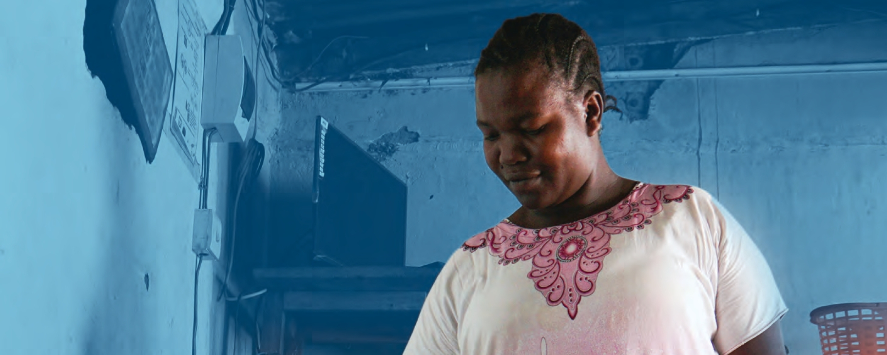 Woman standing in a kitchen with walls painted blue using an electric cooker