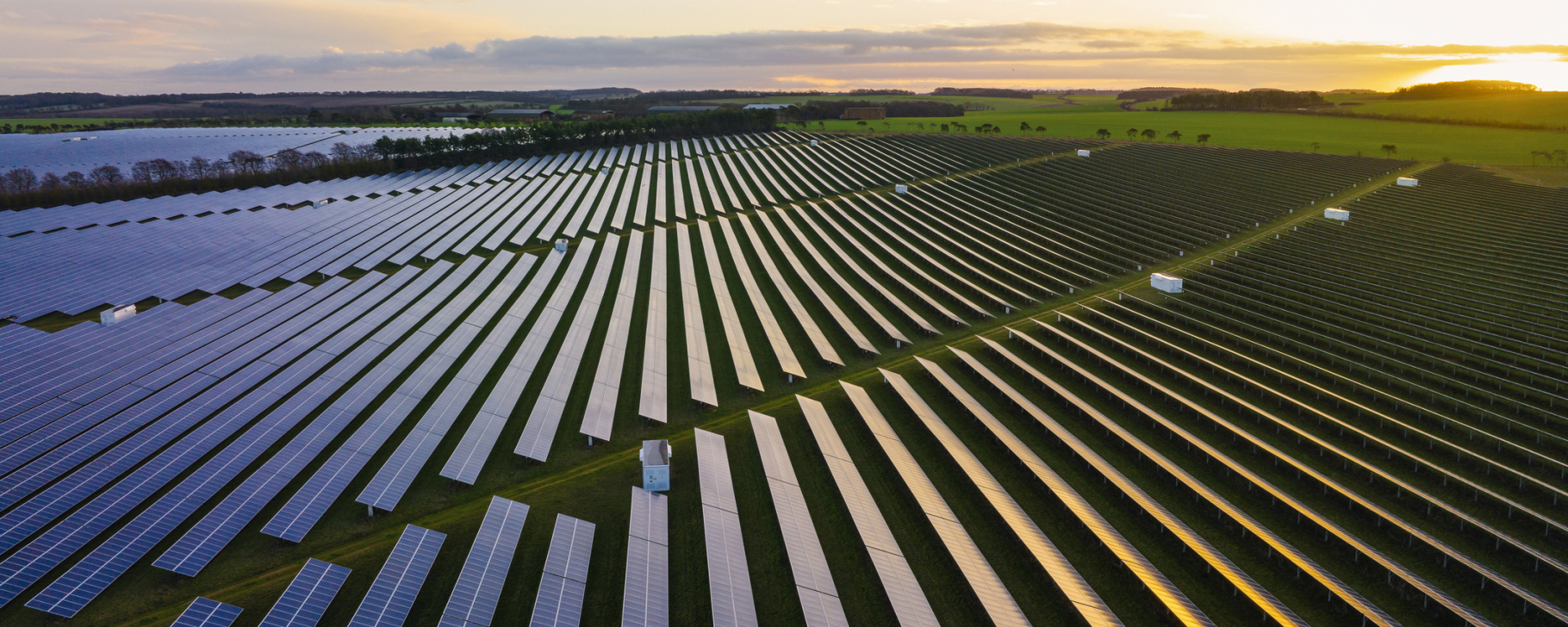 Aerial view of a large solar power installation covering a plain green land.