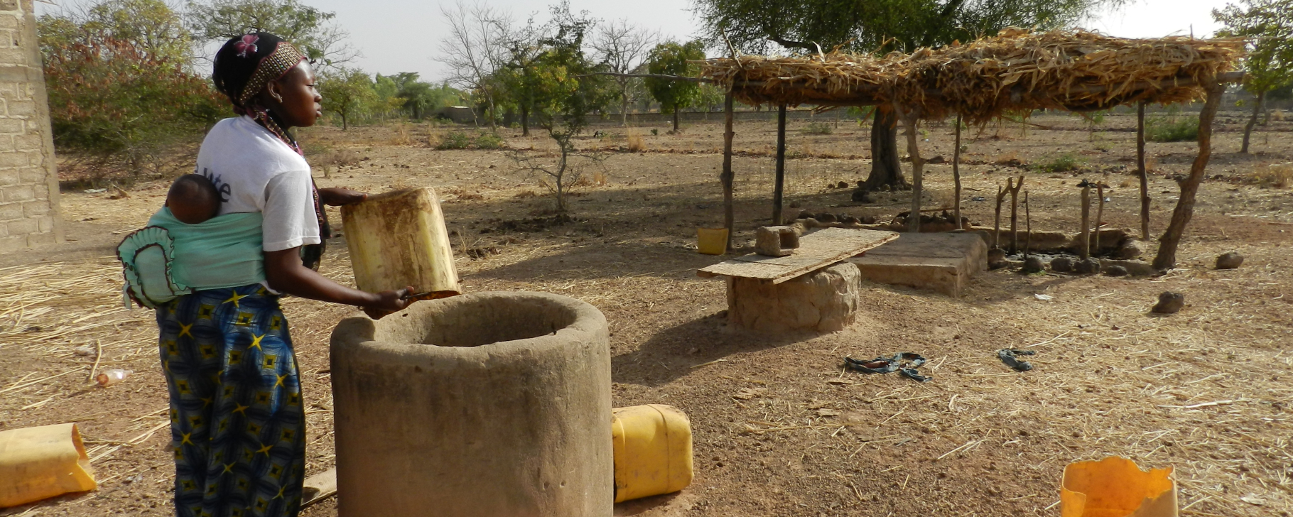 Woman with a child drawing water from a well in Africa