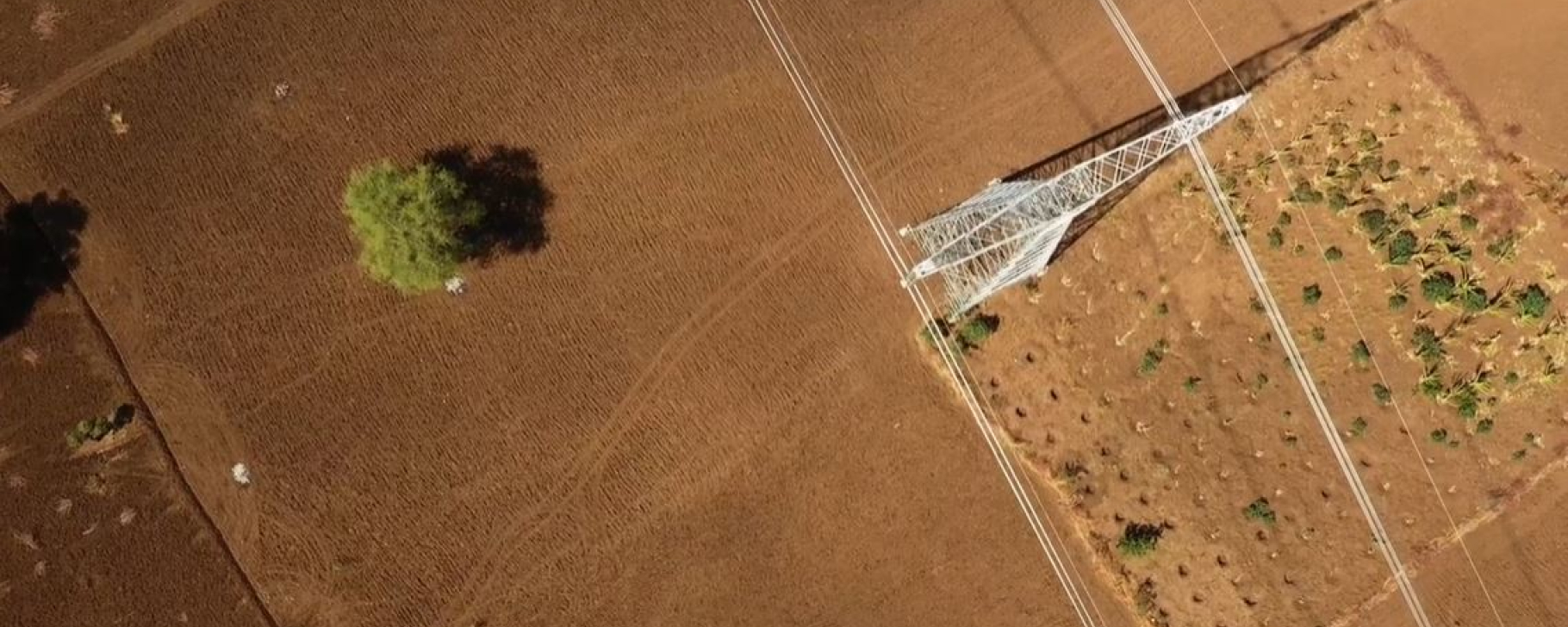 Birdseye view of a baren land with a land powerline 