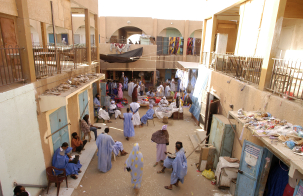 People gather and shop in a busy indoor market courtyard.