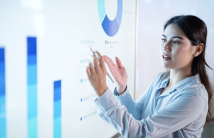 A woman presents data using charts and graphs on a digital display.