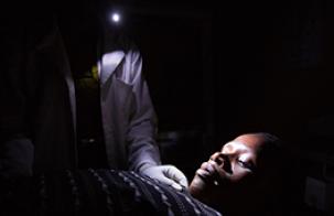 Tanzania midwife at night holding cell phone in mouth Tanzania midwife at night holding cell phone in mouth. Photo credit: We Care Solar