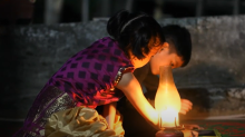 children doing homework on electronic table next to a kerosene lamp
