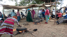 women and men gathering, cooking, fire