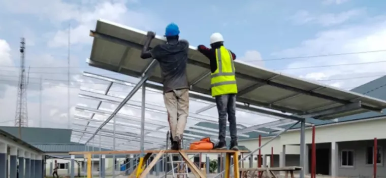 workers install a solar array at a large hospital in Nigeria.