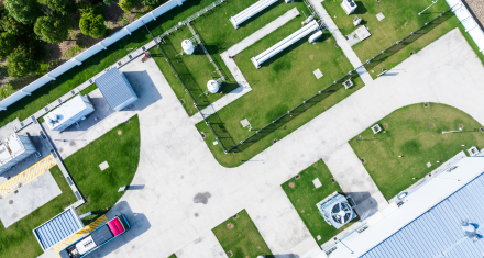 Aerial view of an industrial energy facility with equipment, pipelines, buildings, and roads.