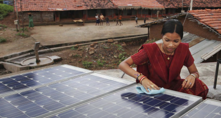 Jobs in Energy Person cleaning a solar panel installation on a rooftop in a rural community