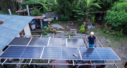 Access to Electricity Rooftop solar panels installed at a home, with a worker cleaning panels in a rural setting.