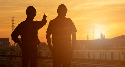Two people looking towards the sunset in an industry setting