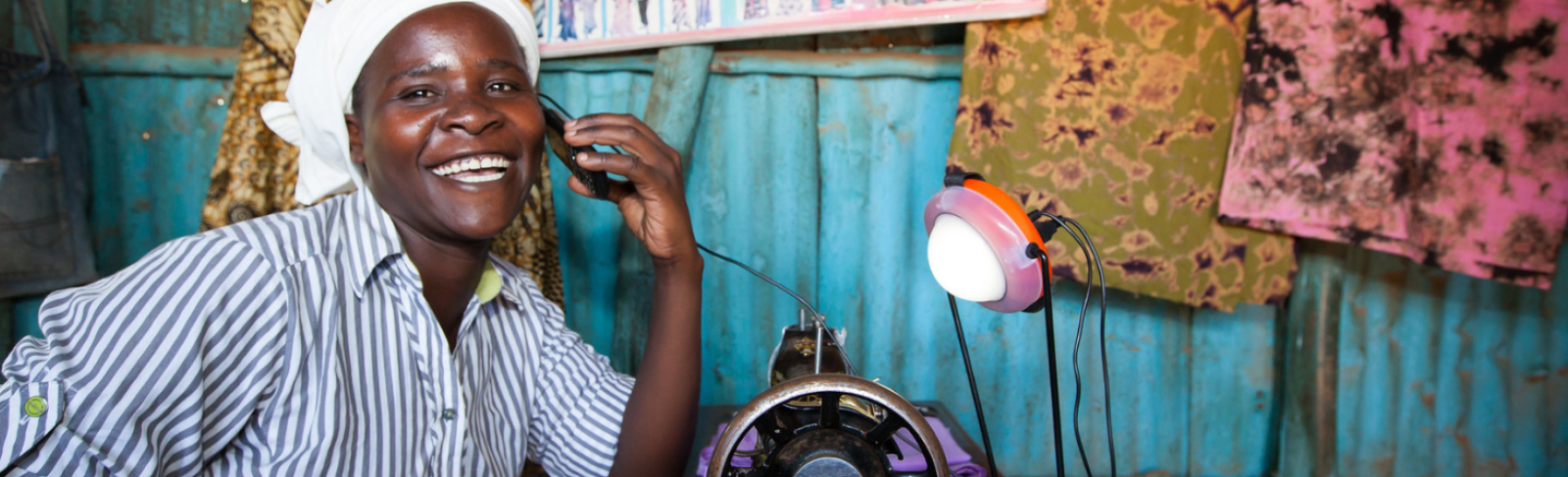 Rose Owino a tailor in Migori, uses a solar light to charge her phone during the day, Migori, Kenya