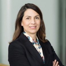 Gabriela Elizondo Azuela Professional portrait of a person with shoulder‑length hair, wearing a dark blazer and light blouse, standing with arms crossed against a neutral background.