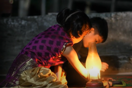 children doing homework on electronic table next to a kerosene lamp