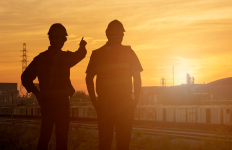 Two people looking towards the sunset in an industry setting