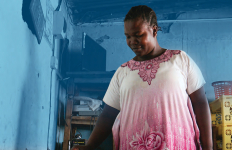 Woman standing in a kitchen with walls painted blue using an electric cooker