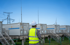 Person stands outdoors at an industrial energy storage facility