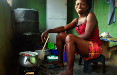 Person sitting on a small stool while preparing a meal